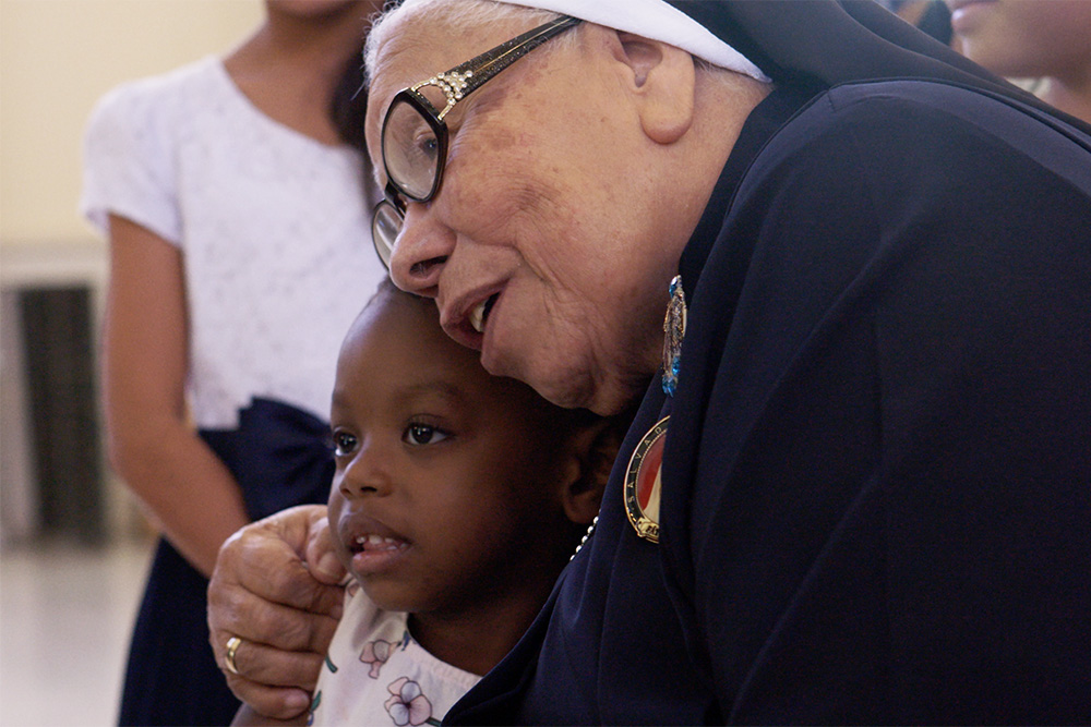 La Hna. María Rosa Legoll, de las Hermanas Escolares de San Francisco, abraza a un niño en el documental With This Light. (Foto: cortesía de Miraflores Films)